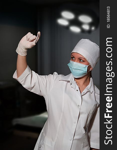 Young pretty surgeon holding nail for osteosynthesis in operating room