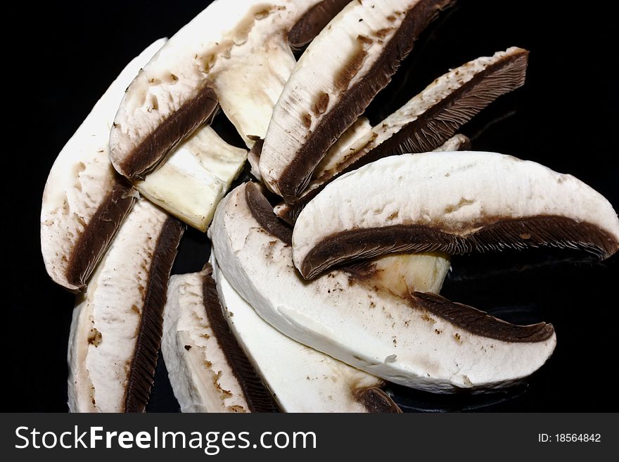 Sliced large uncooked mushrooms one on top of another on a brown background. Sliced large uncooked mushrooms one on top of another on a brown background