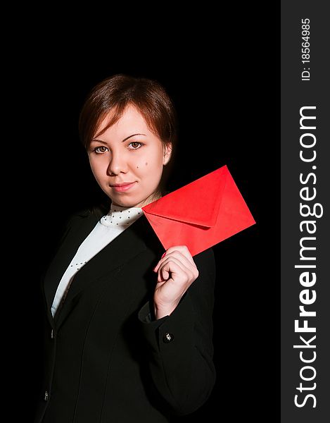 Pretty young business woman smiles and holds blank envelope isolated on black. Pretty young business woman smiles and holds blank envelope isolated on black