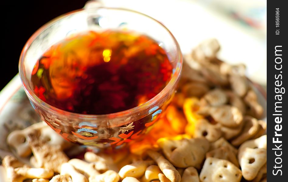 Closeup image of ceramic plate with crackers on it and a glass cup of tea. Closeup image of ceramic plate with crackers on it and a glass cup of tea