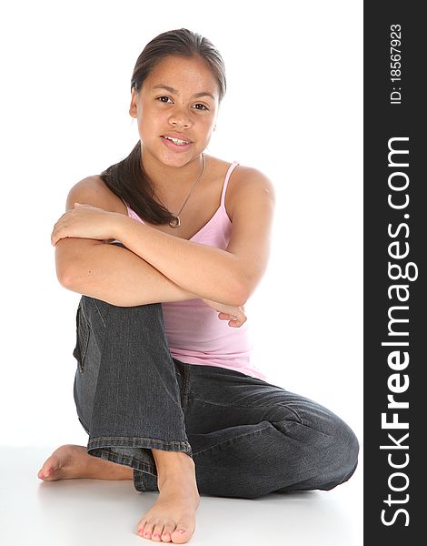 Young teenager, 13 year old girl, sitting on floor in relaxed pose. She is wearing blue jeans, a pink top but is barefoot. Young teenager, 13 year old girl, sitting on floor in relaxed pose. She is wearing blue jeans, a pink top but is barefoot.