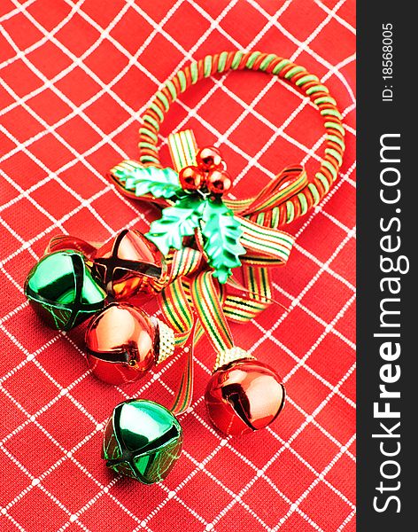 Shiny Christmas jingle bells in red and green with red and white textured cloth background, vivid color. Shiny Christmas jingle bells in red and green with red and white textured cloth background, vivid color