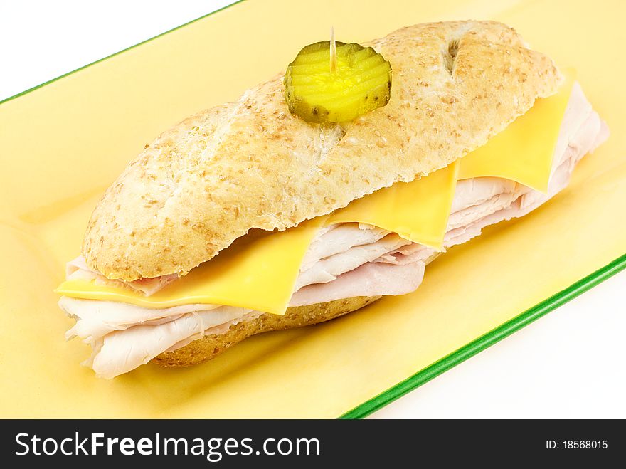 A whole turkey submarine Sandwich with american cheese on wheat bread, served on a yellow plate