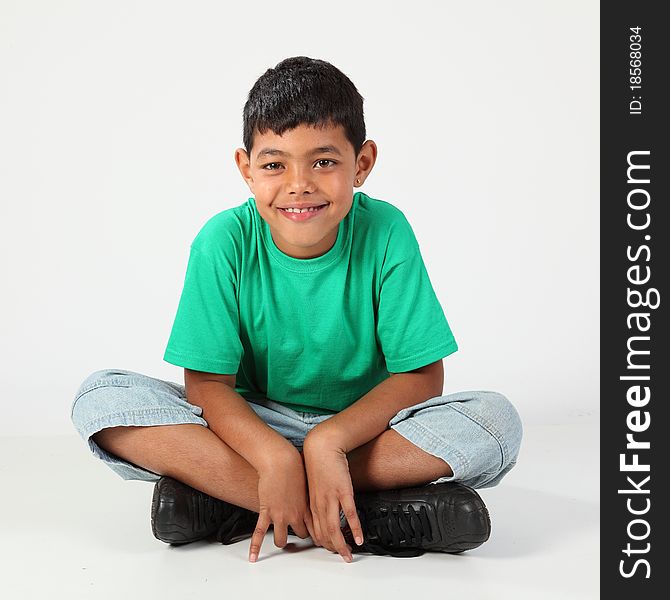 Young school boy, 10, sitting cross legged on the floor, wearing green t-shirt. Young school boy, 10, sitting cross legged on the floor, wearing green t-shirt.