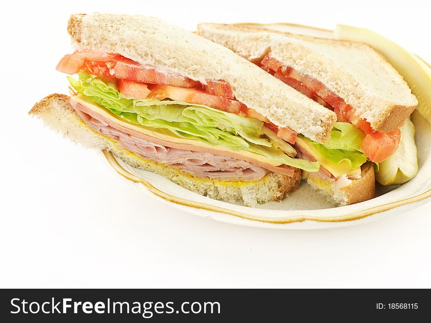 A delicious healthy ham, cheese and bologna sandwich, cut in half on a plate, white copy space. A delicious healthy ham, cheese and bologna sandwich, cut in half on a plate, white copy space