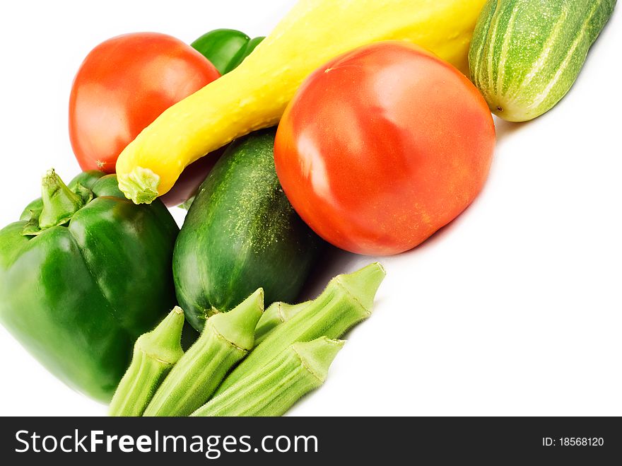 A collection of fresh summer vegetables with vivid color on a white background, diagonal viewpoint. A collection of fresh summer vegetables with vivid color on a white background, diagonal viewpoint