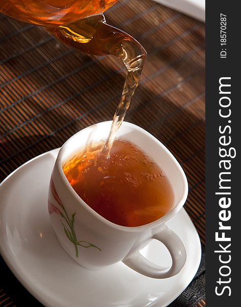 Pouring of tea from a transparent teapot close up. Pouring of tea from a transparent teapot close up