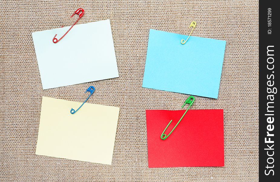 Blank color adhesive notes attached with safety pins to canvas background. Blank color adhesive notes attached with safety pins to canvas background