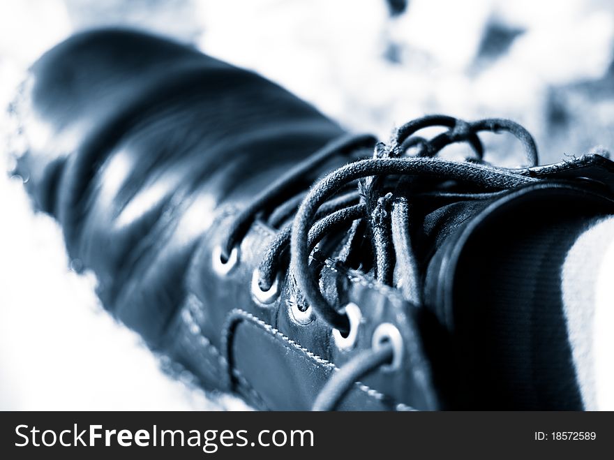 Blue toned image of an old men shoe with untied laces