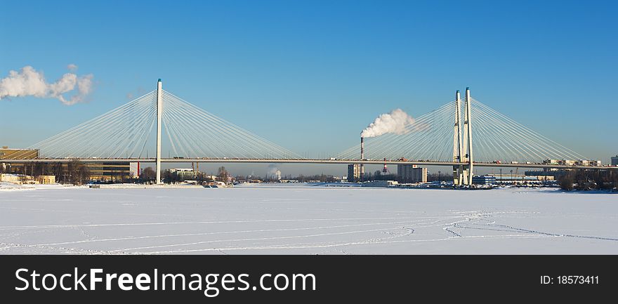 Big cable-stayed bridge across the frozen river in winter