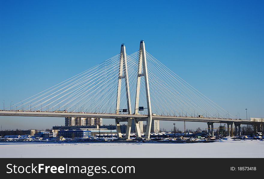 Big cable-stayed bridge across the frozen river in winter
