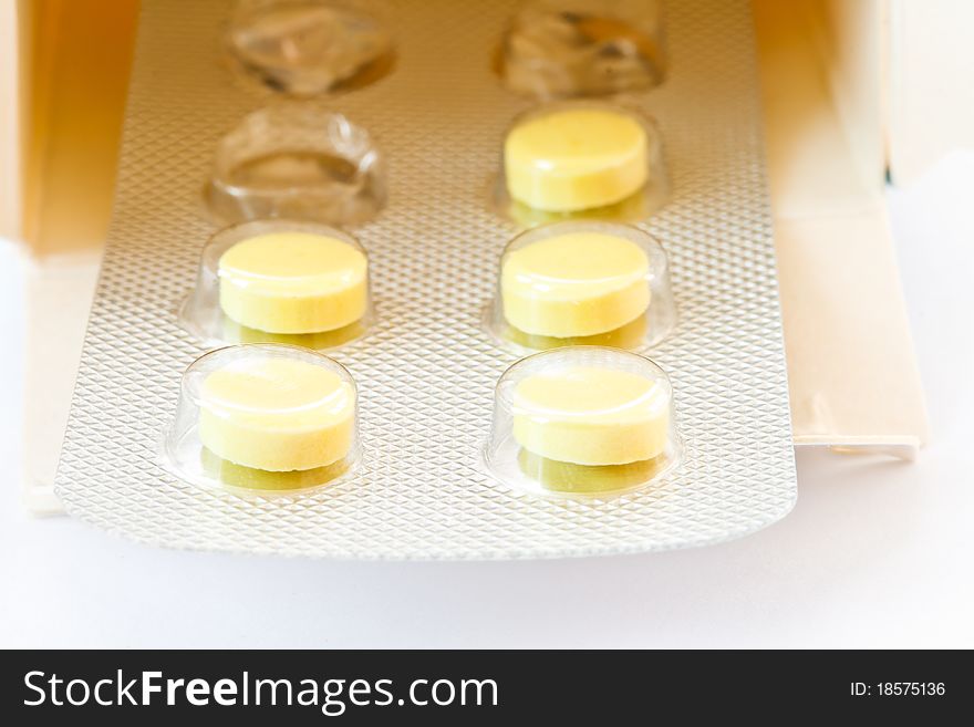 Yellow tablets in the packaging box is isolated on a white background. Yellow tablets in the packaging box is isolated on a white background
