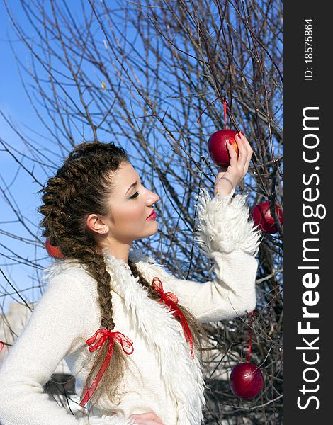 Outside portrait of beautiful young woman with eyes shut with red apple in park. Outside portrait of beautiful young woman with eyes shut with red apple in park