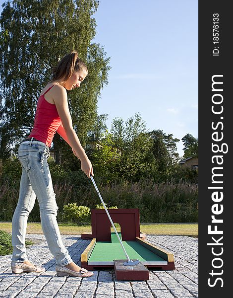 Attractive Young Woman Putting Golf Ball On Green