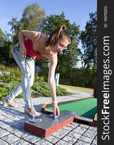 Attractive Young Woman Putting Golf Ball On Green