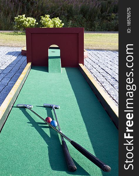 Set of mini golf clubs and color balls on green