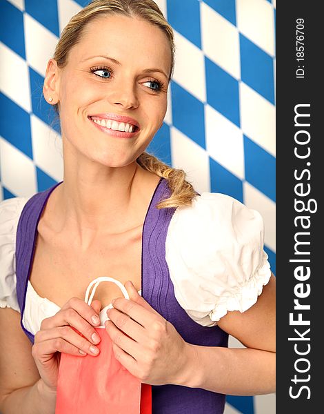 Woman wearing bavarian dress is holding a red paper bag. Woman wearing bavarian dress is holding a red paper bag