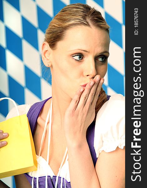 Woman wearing a bavarian dress is holding a yellow paper bag. Woman wearing a bavarian dress is holding a yellow paper bag