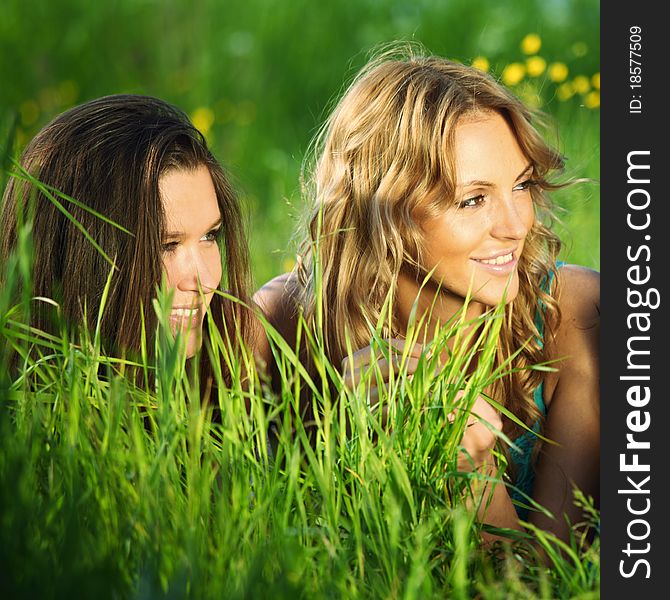 Girlfriends lays on green grass and smile. Girlfriends lays on green grass and smile