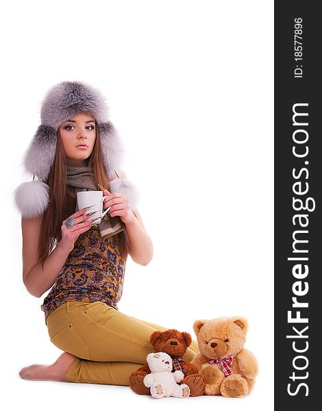Beautiful brunette in a fur hat sitting next to a few teddy bears