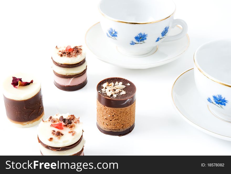 Two cups with cornflowers and four cakes on a white background. Two cups with cornflowers and four cakes on a white background