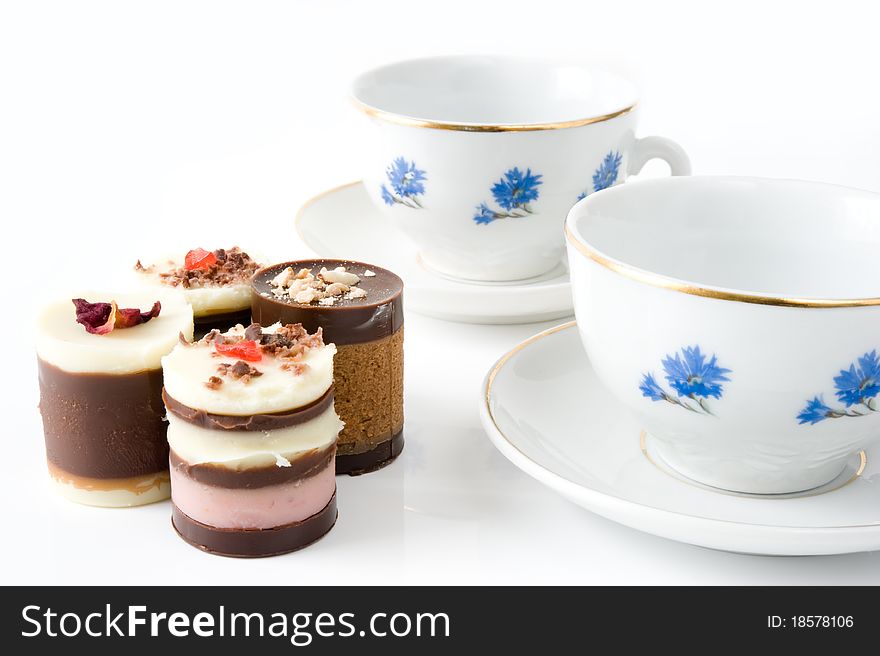 Two cups with cornflowers and four cakes on a white background. Two cups with cornflowers and four cakes on a white background