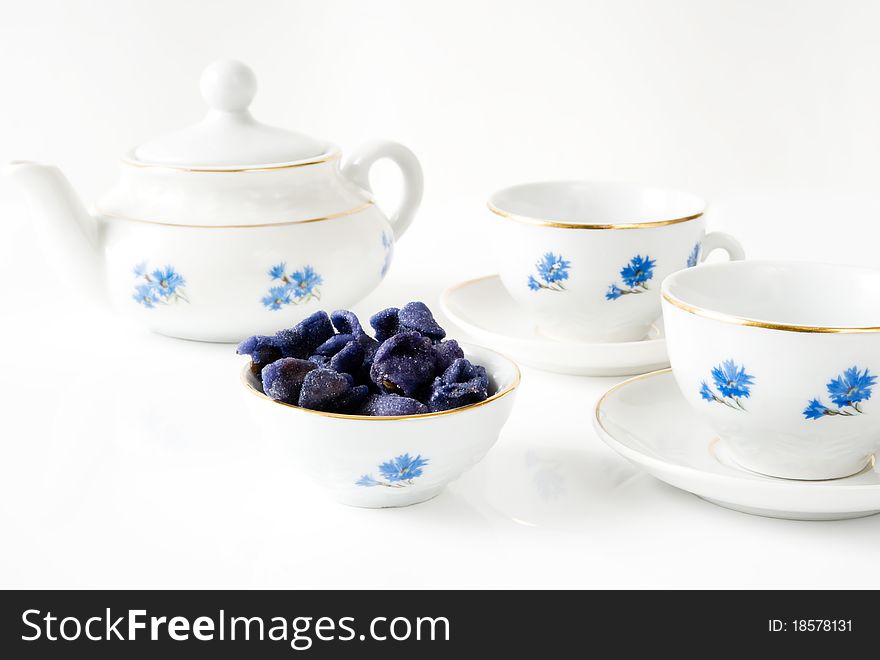 Teapot, two cups with cornflowers and candied violets in a bowl. Teapot, two cups with cornflowers and candied violets in a bowl