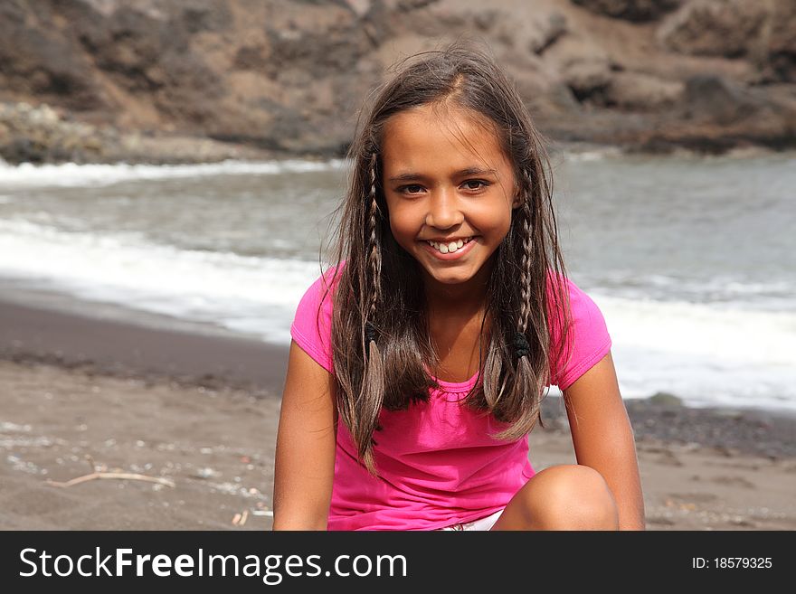 Pretty young smiling school girl sitting on beach