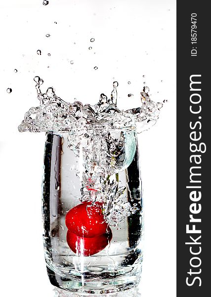 Two red cherrys splashing into a glass