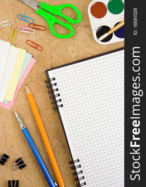 School accessories and checked notebook on wooden table