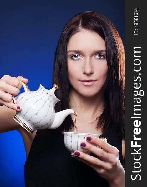 Beautiful girl pouring tea from a teapot into a cup. Beautiful girl pouring tea from a teapot into a cup