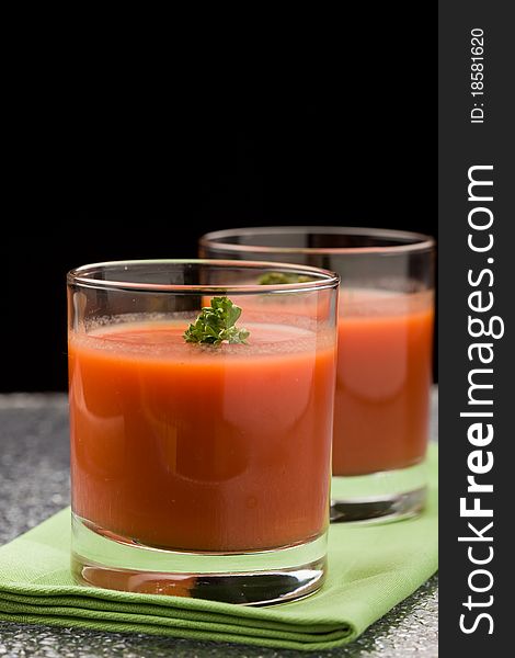 Photo of delicious tomatoe juice with parsley in glass on green cloth