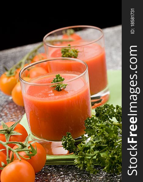 Photo of delicious tomatoe juice with parsley in glass on green cloth