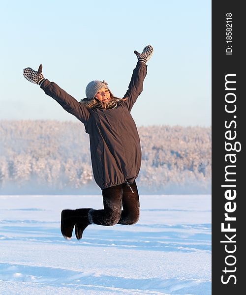 Girl jumps in the snow in the sun