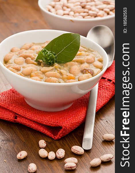 Photo of delicious beans soup on red cloth standing on wood table