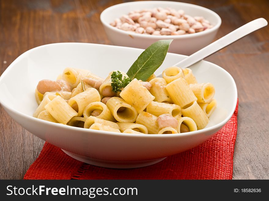 Photo of delicious pasta with beans and parsley standing on wood table