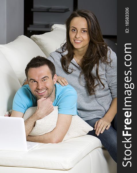 Happy young couple with laptop on white sofa