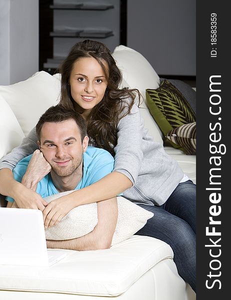 Happy young couple with laptop on the white sofa