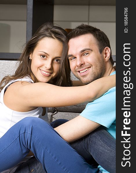 Young couple sits on a white sofa embracing. Young couple sits on a white sofa embracing