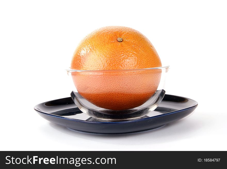 Grapefruit in a glass vase on a dark blue plate, white background