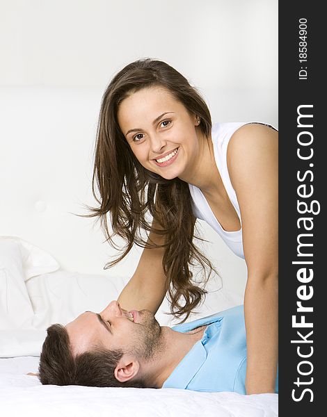 Young couple lying on a white sofa embracing and smiling. Young couple lying on a white sofa embracing and smiling