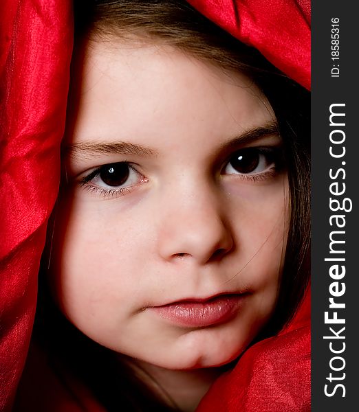A picture of a young girl playing fashion model in a red scarf. A picture of a young girl playing fashion model in a red scarf