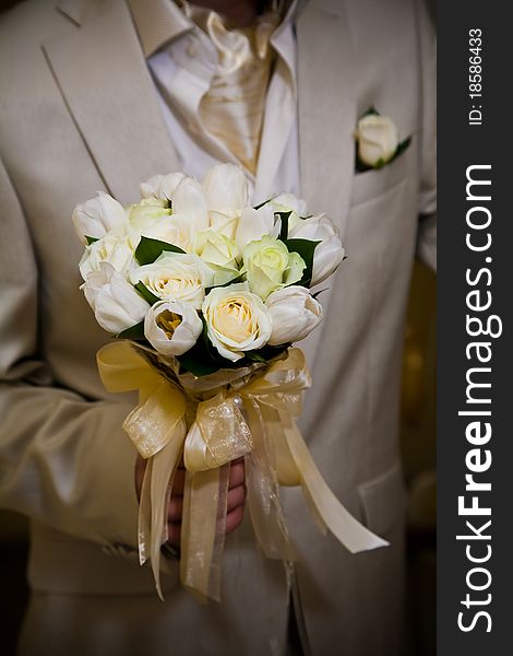 Groom holding wedding bouquet with roses and tulips