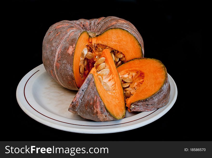 Ripe fresh raw pumpkin on plate isolated over black background. Ripe fresh raw pumpkin on plate isolated over black background