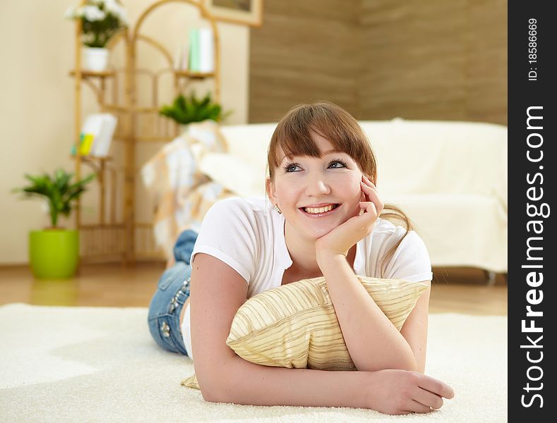 A young girl with at home relaxing on the carpet in her living room. A young girl with at home relaxing on the carpet in her living room
