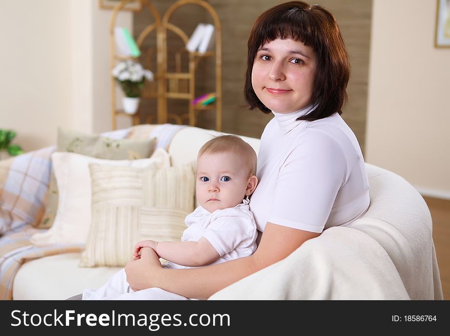 A young mother playing with her infant baby at home. A young mother playing with her infant baby at home