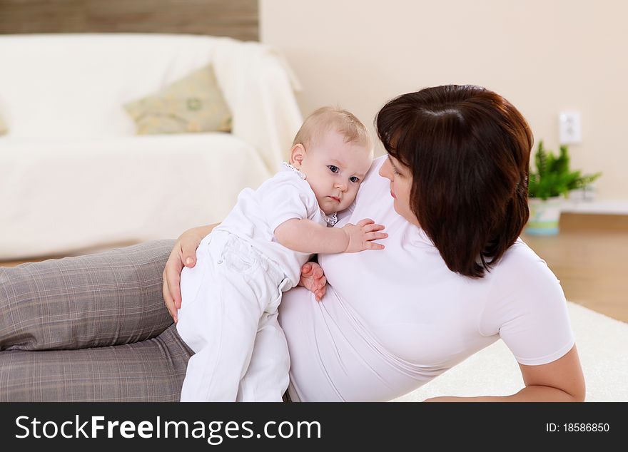 A young mother playing with her infant baby at home. A young mother playing with her infant baby at home