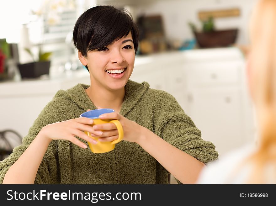 Multi-ethnic Young Attractive Woman Socializing with Friend in Her Kitchen. Multi-ethnic Young Attractive Woman Socializing with Friend in Her Kitchen.