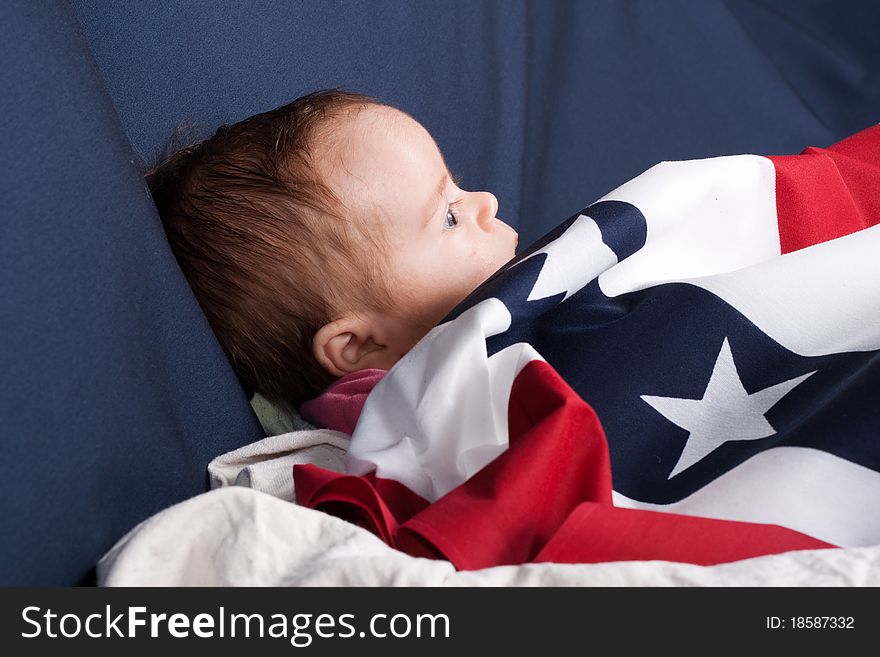Baby covered with an American Flag pattern. There is a blue background and room to add text. Baby covered with an American Flag pattern. There is a blue background and room to add text.