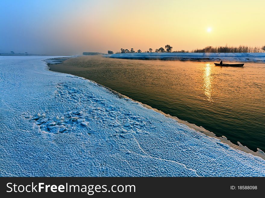 Calm winter landscape of a lake and trees during sunset.